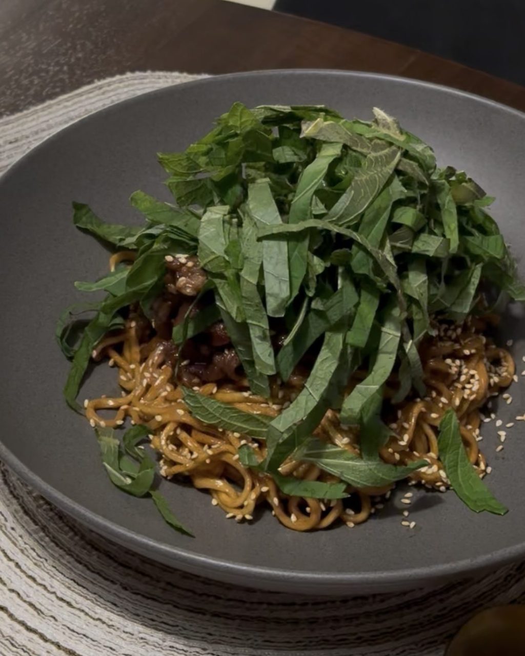 Bowl of creamy pasta with bulgogi beef topped with thinly sliced perilla leaves and sesame seeds