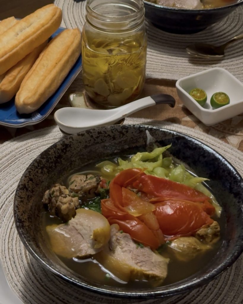Table set with bún dọc mùng, fried dough sticks, a jar of pickles and calamansi on the side