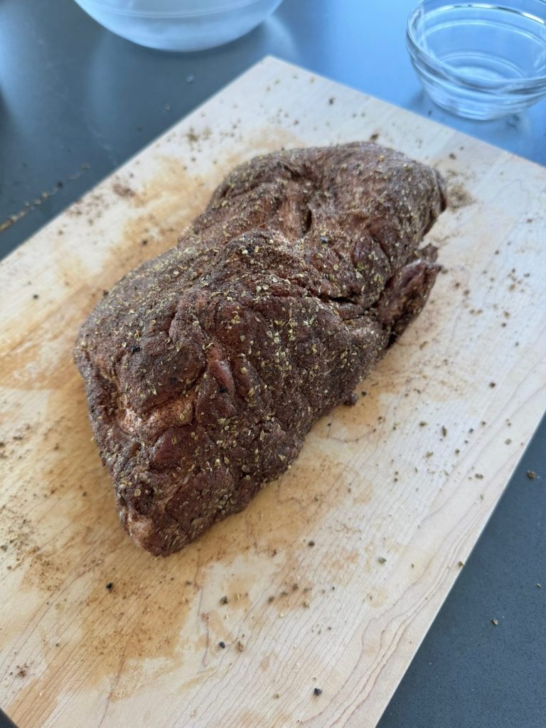 Pork shoulder rubbed with chili powder, oregano and cumin on a wooden cutting board