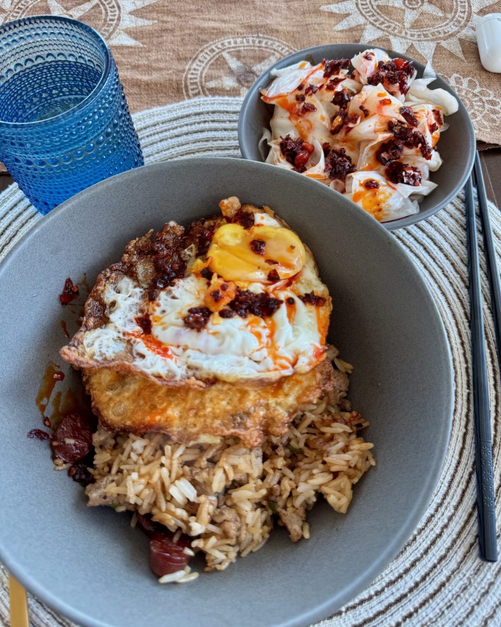 Bowl of kimchi fried rice with diced sausage, topped with a crispy fried egg and chili crisp