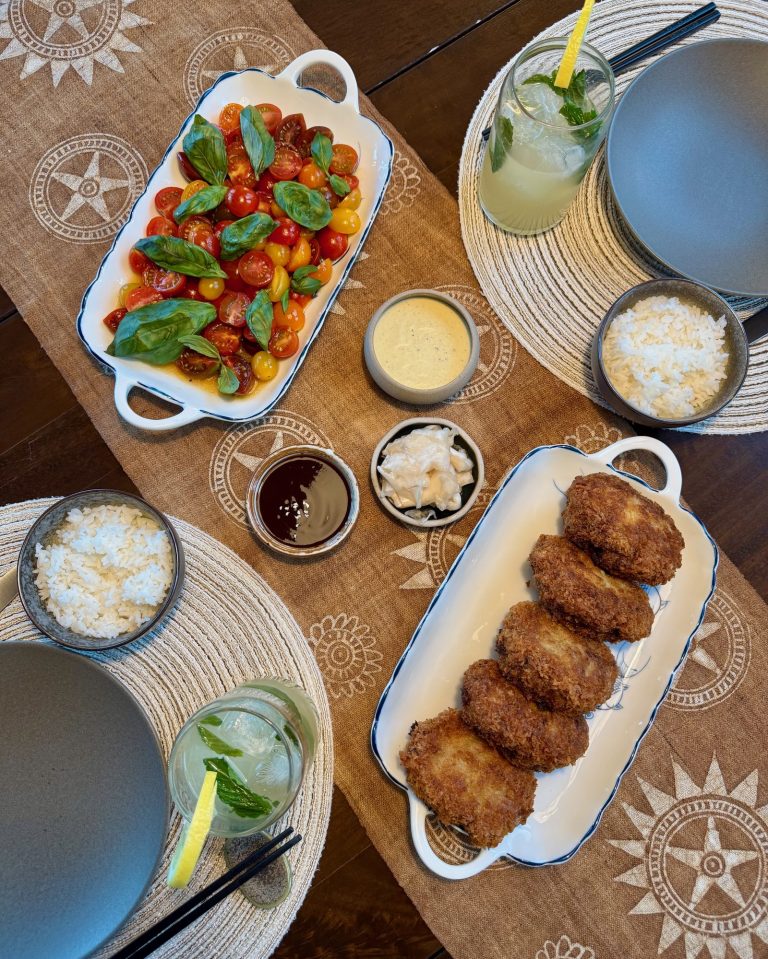 Overhead table spread of fried pork cutlets, a cherry tomato basil salad, tonkatsu sauce, tartar sauce and bowls of rice