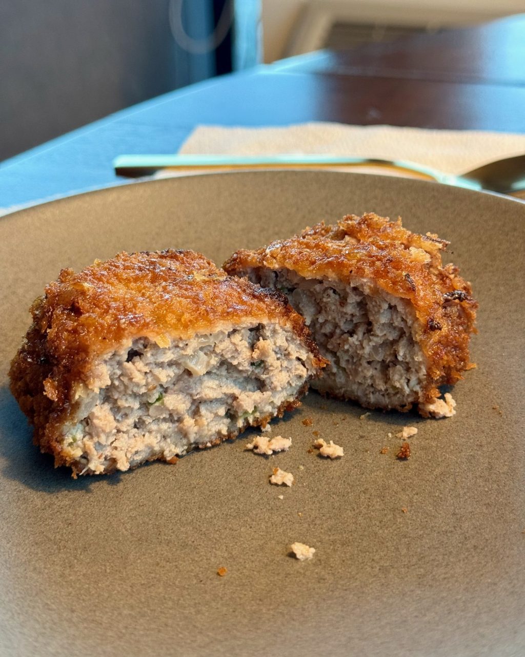A crispy panko-crusted ground pork cutlet cut in half to show the juicy inside