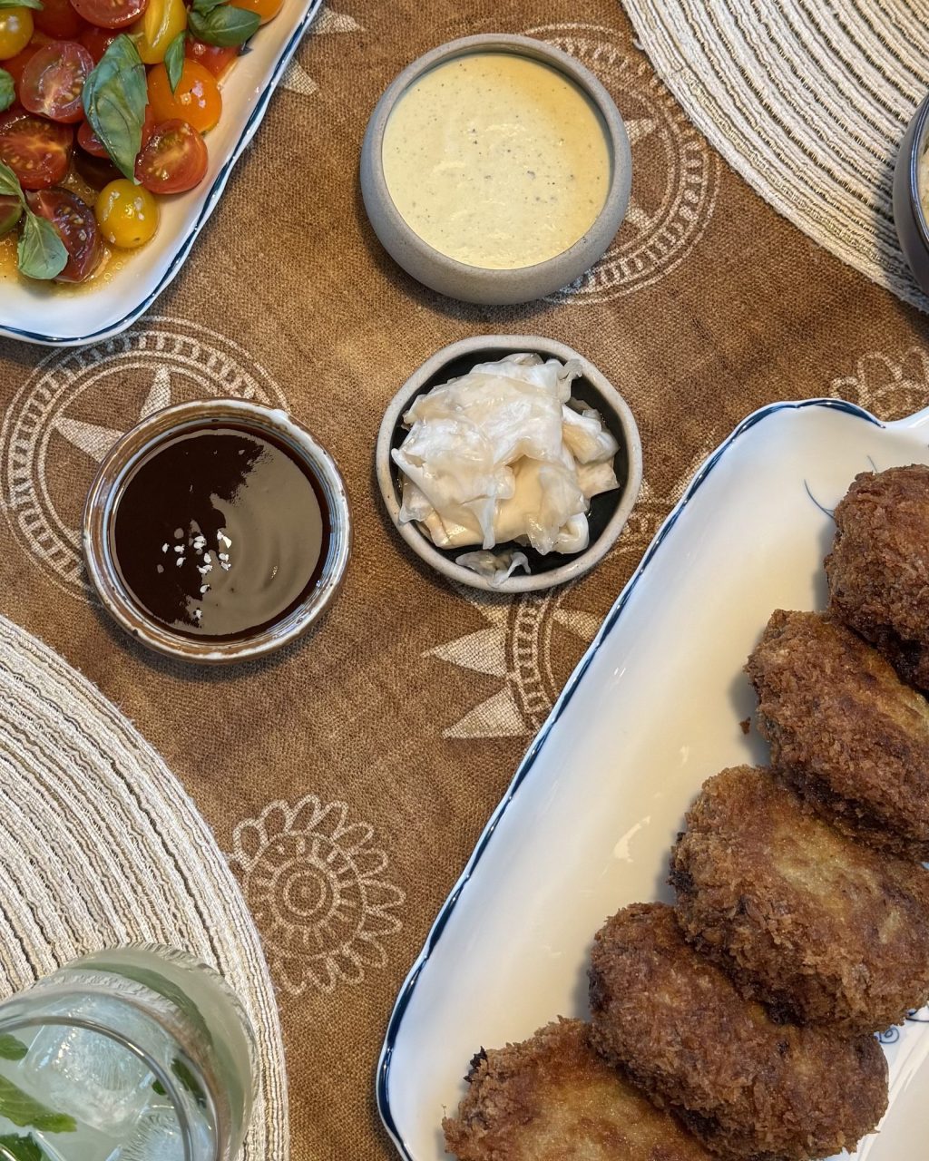 Small bowls of glossy dark tonkatsu sauce, creamy jalapeño tartar sauce and shredded cabbage next to a platter of fried pork cutlets
