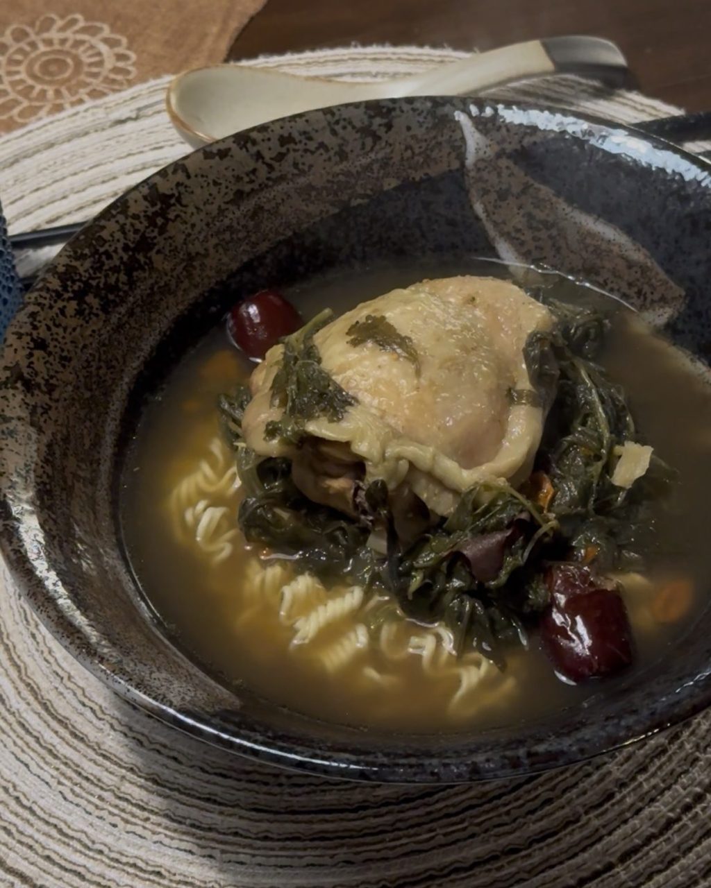 Bowl of herbal chicken soup with mugwort, red dates and noodles in a dark broth