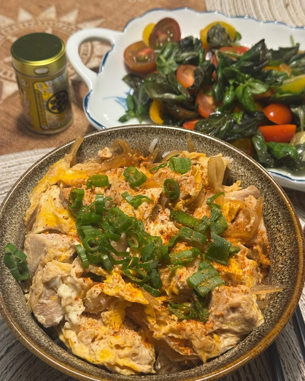 Bowl of oyakodon with chicken and soft-set egg over rice, topped with scallions and togarashi