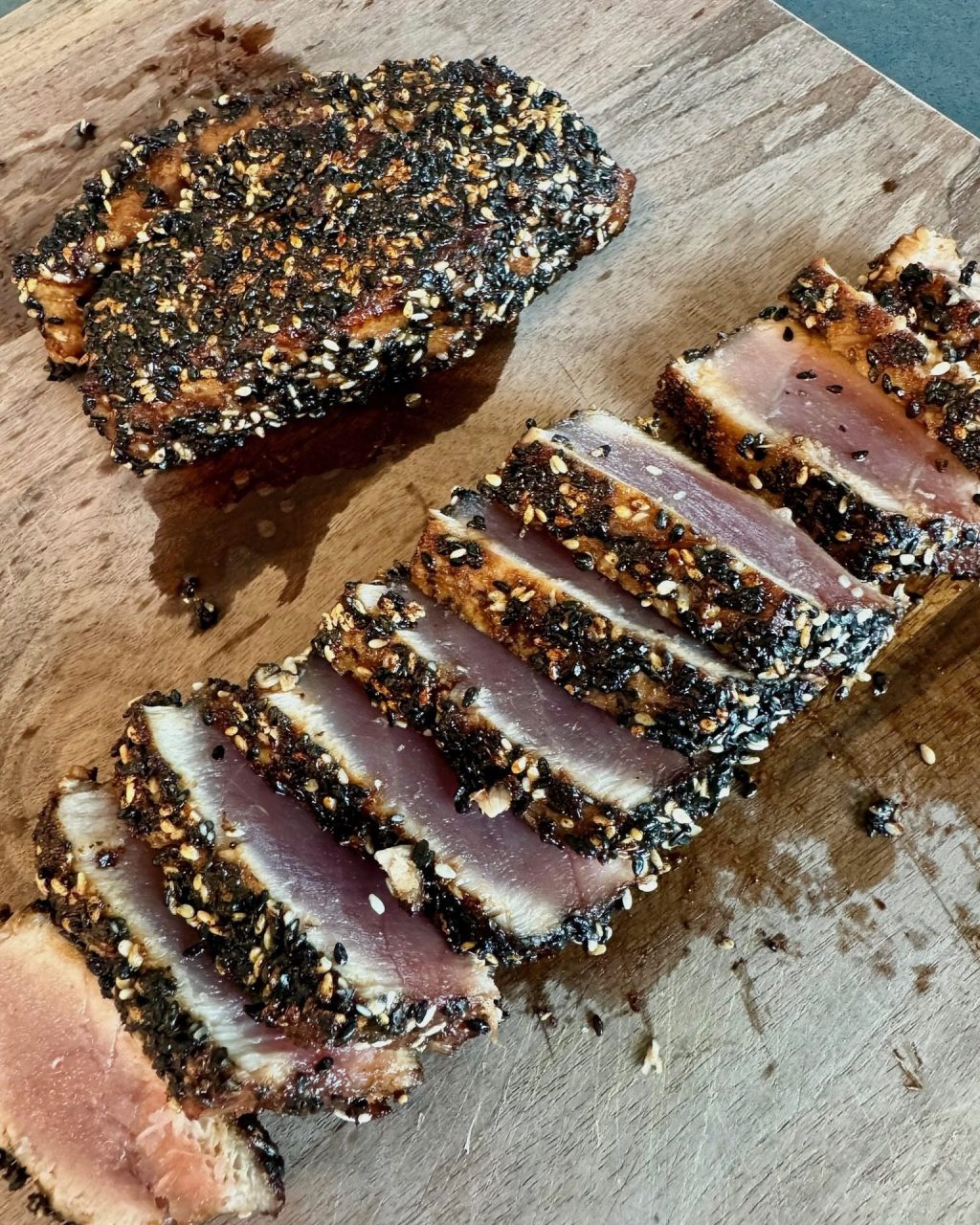 Sesame-crusted ahi tuna seared on the outside and rare inside, sliced on a wooden board