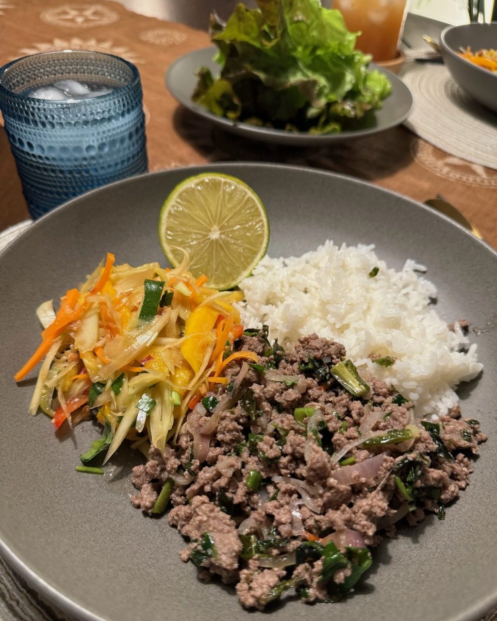 Shredded green papaya and carrot salad with lime, served on a plate with rice and ground meat