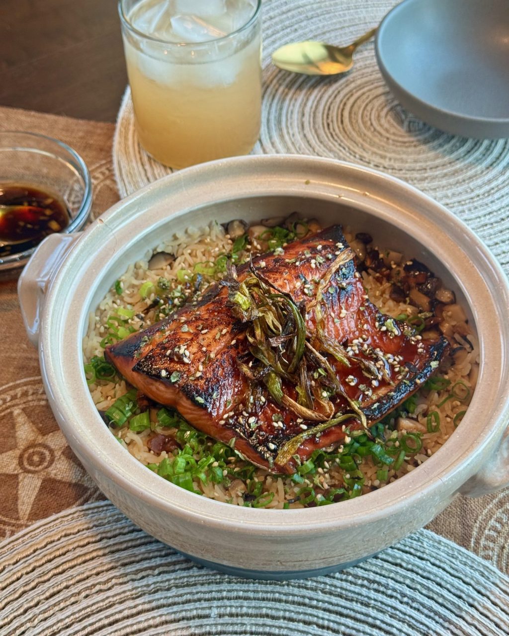 Clay pot of rice topped with a glazed salmon fillet, crispy scallions and green onions