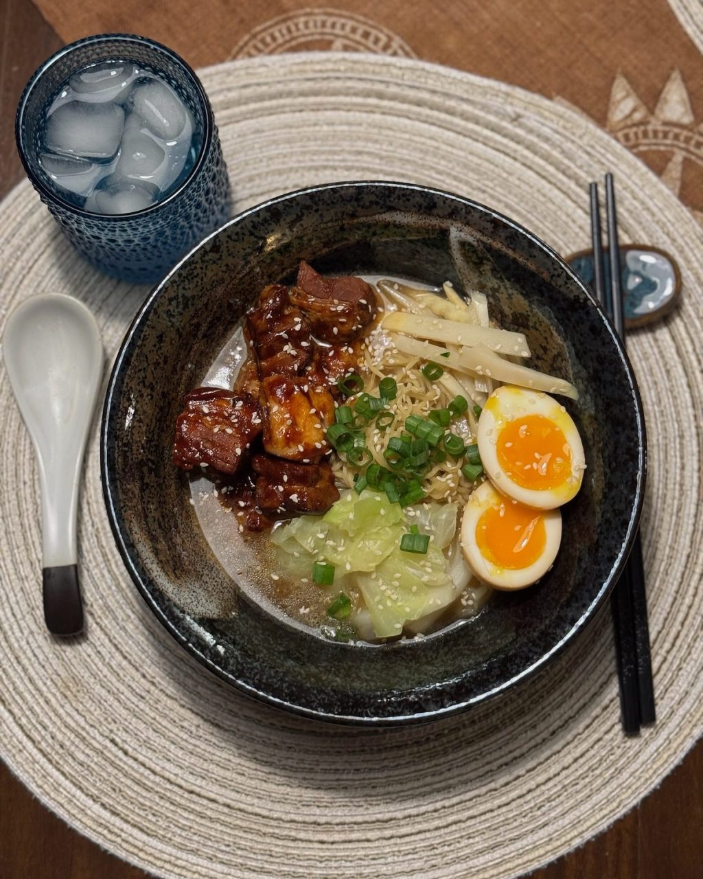Bowl of ramen with glazed pork belly, soft-boiled eggs, bamboo shoots, cabbage and green onion