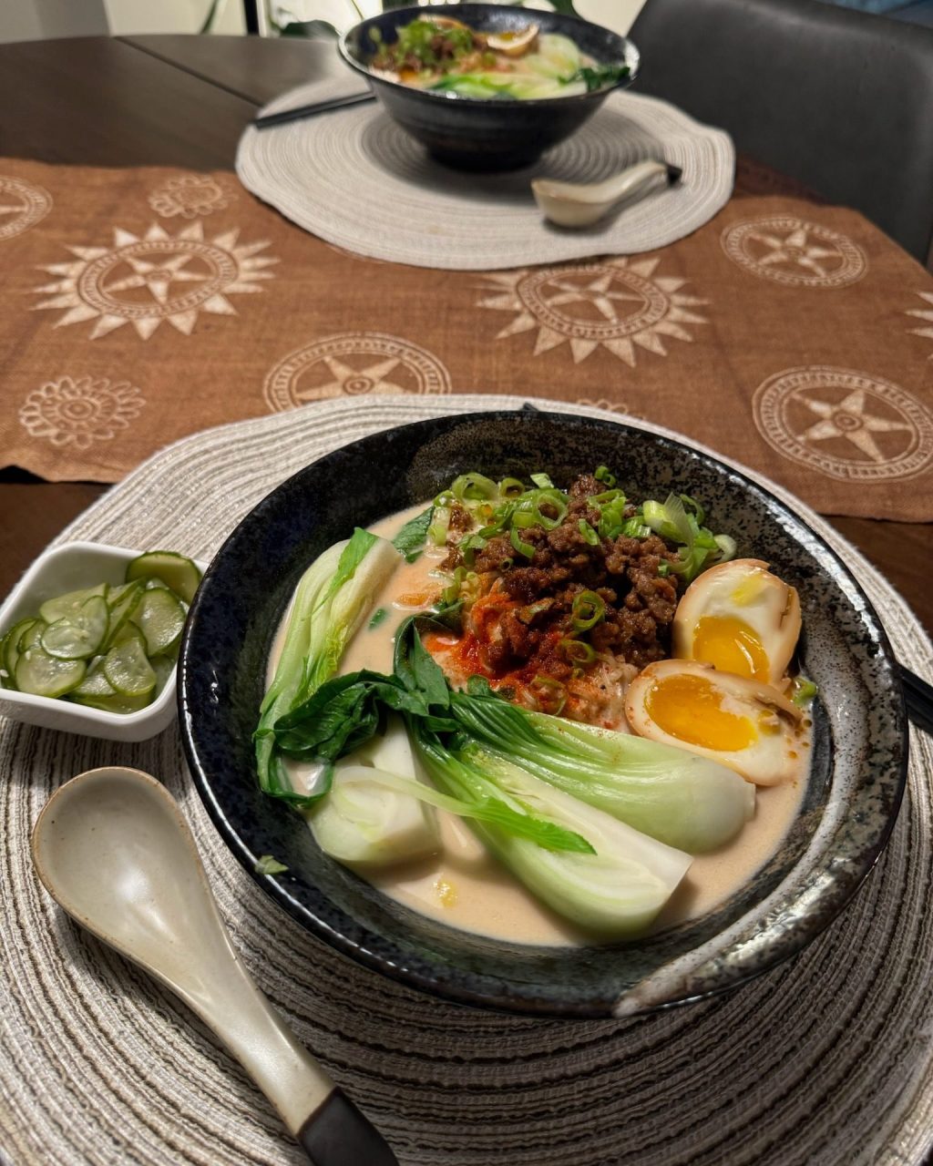 Bowl of creamy tantanmen ramen topped with spicy ground pork, bok choy, soft-boiled eggs and green onion