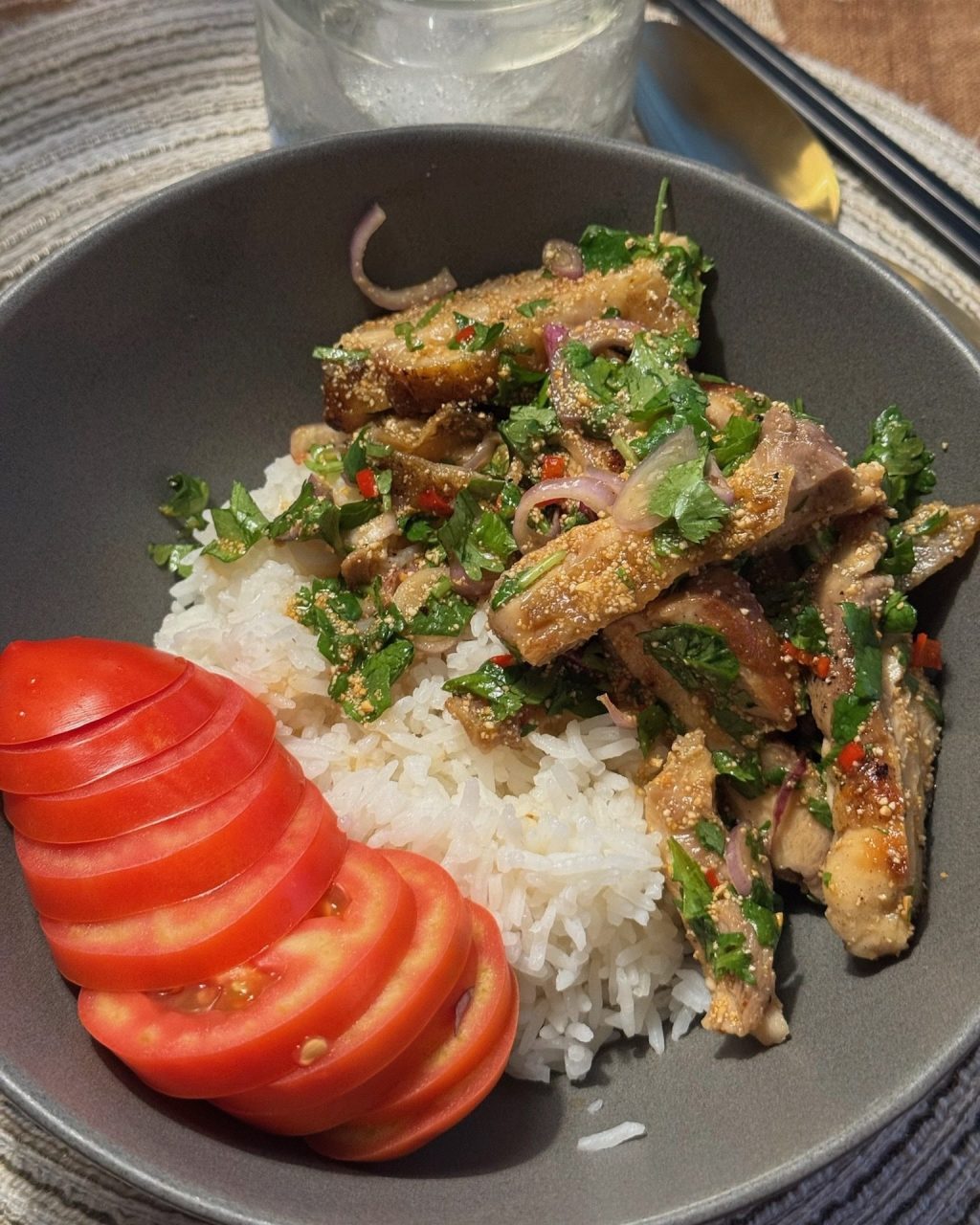Sliced crispy chicken thigh tossed with toasted rice powder, cilantro, shallot and chili over white rice with sliced tomato
